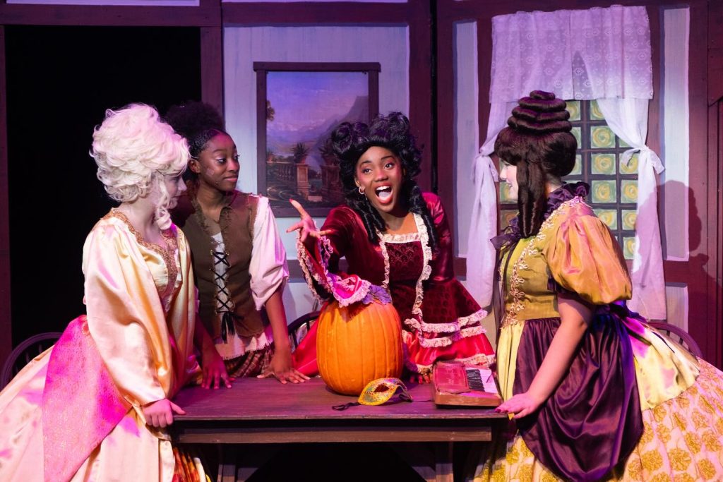 stepmother and family from cinderella behind a table with a pumpkin