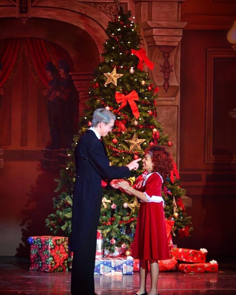 Daddy Warbucks and Annie infront of a Christmas Tree 