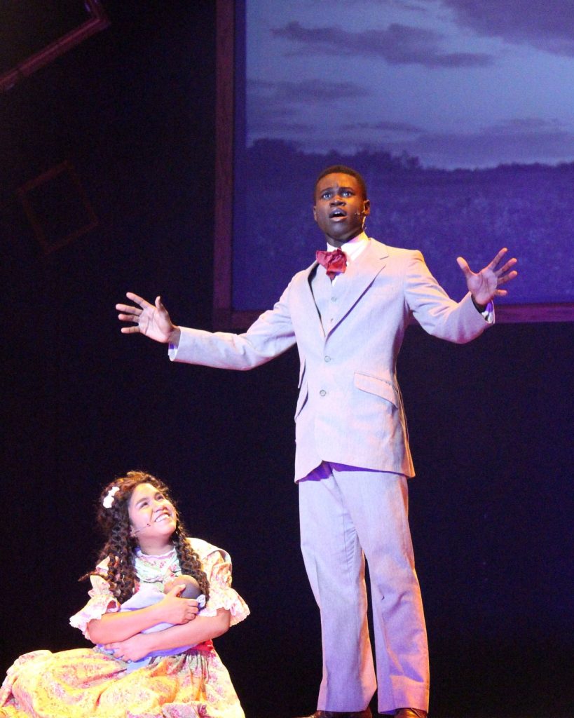 Father, son and baby singing onstage.