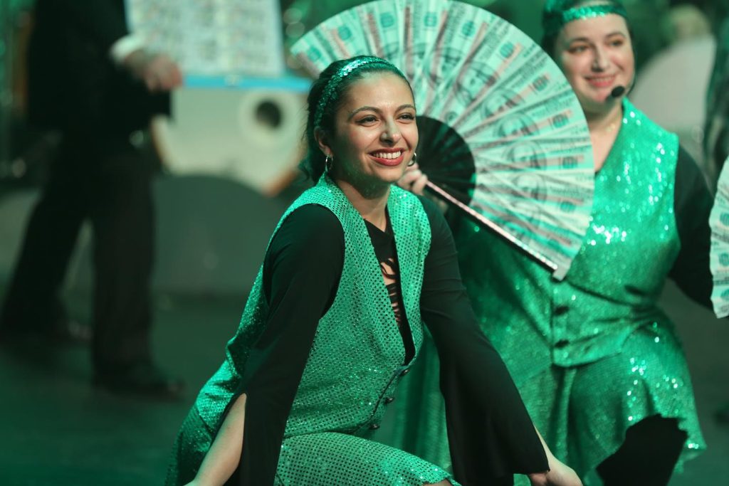 Girl in green costumes with money fan poses for song money money 