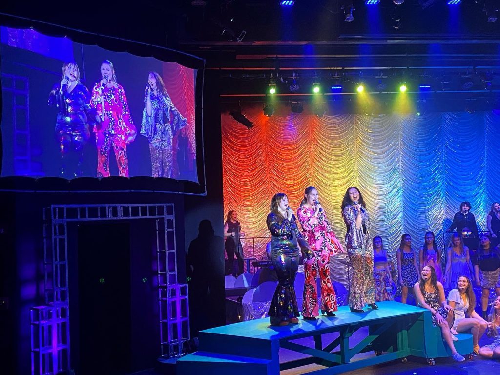 girls in mamma mia costumes sing onstage 