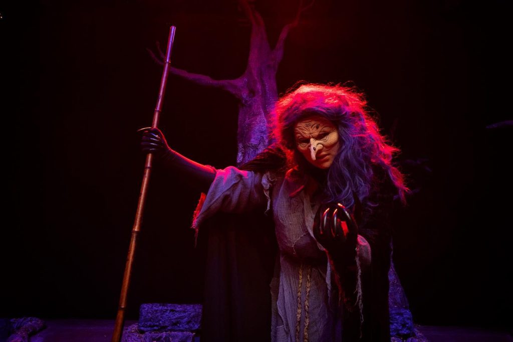 Witch from Into the Woods in red lighting 