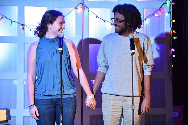 two performers hold hands onstage