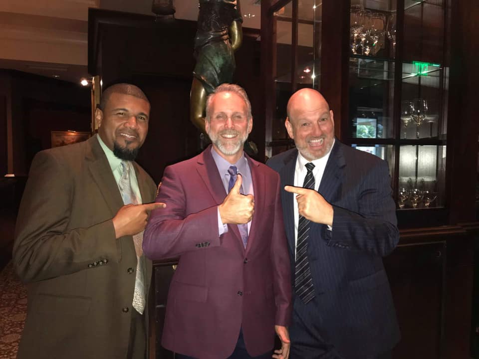 3 men pointing to man in the middle at men of style event 