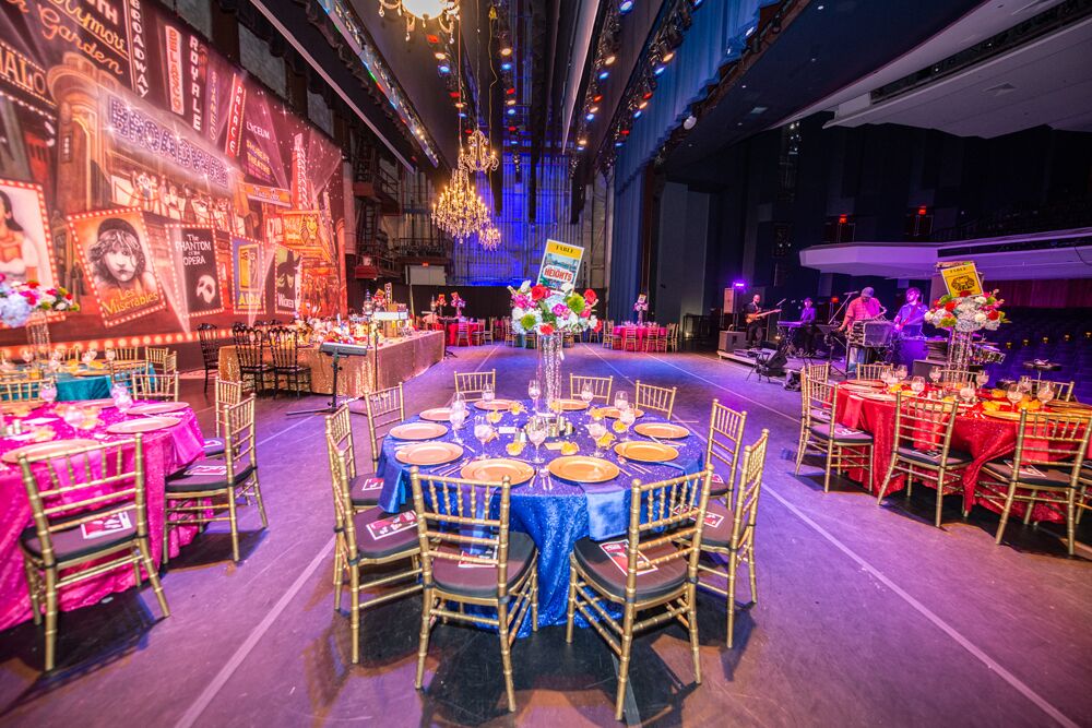 table and chairs set up at a theatre themed gala 