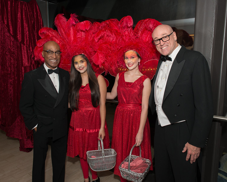 fancy gala greeters in red sparkly outfits with feathers and two gentlemen in tuxedos 